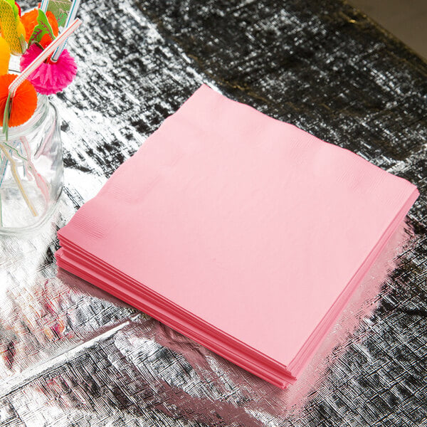 A stack of Classic Pink Creative Converting paper dinner napkins on a table