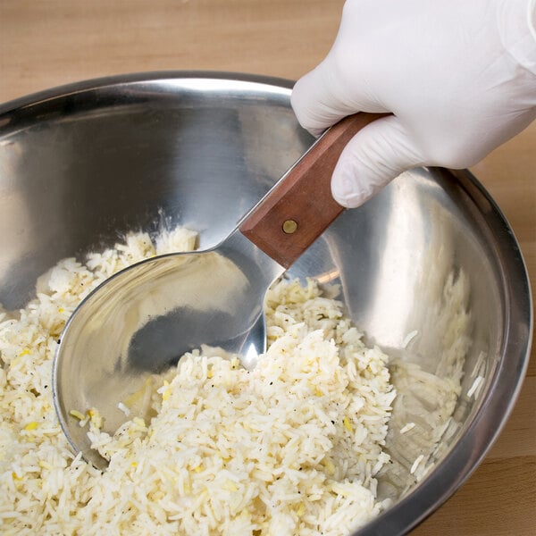 A person using a Town stainless steel rice paddle to scoop rice into a bowl.
