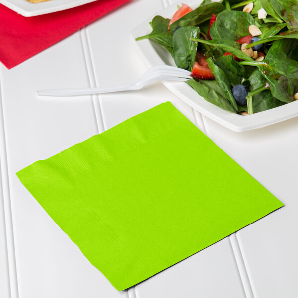 A Fresh Lime green napkin with a bowl of salad and a fork on a white plate.