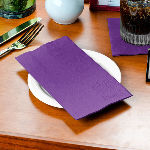 A plate with Creative Converting amethyst paper dinner napkins on it.