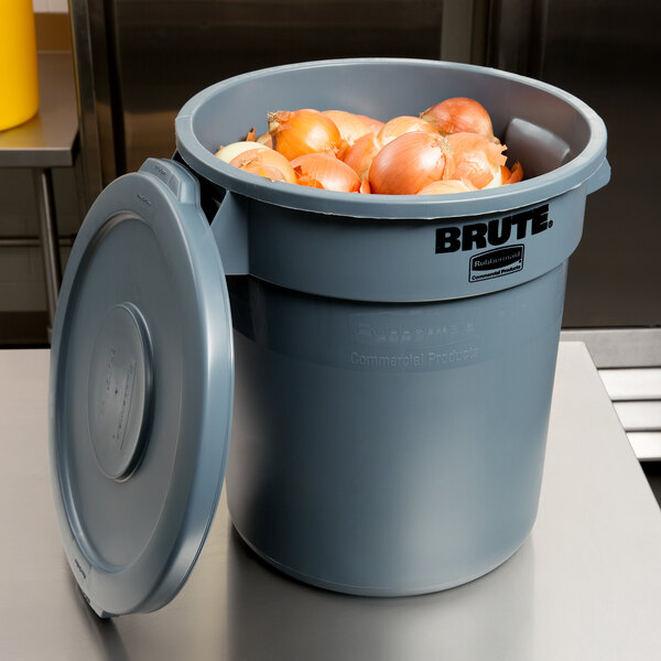A Rubbermaid grey round trash can with onions in it.