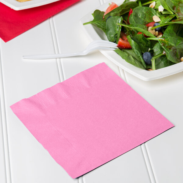 A plate of salad with a pink Creative Converting luncheon napkin on top.