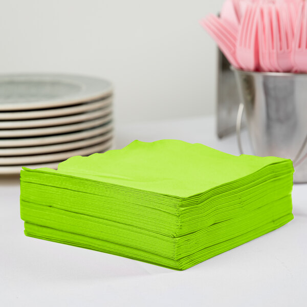 A stack of Creative Converting Fresh Lime Green 3-ply luncheon napkins on a table.