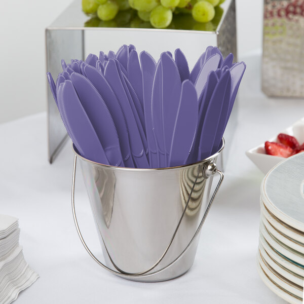 A bucket filled with purple plastic Creative Converting knives.
