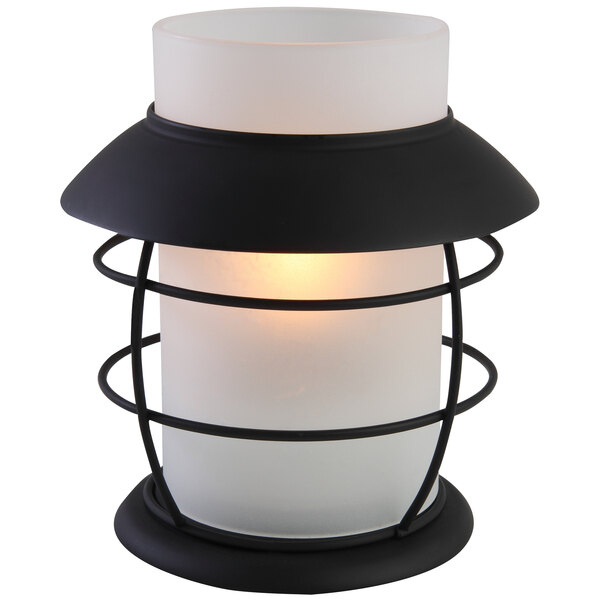 A white glass lantern with a black metal frame containing a white candle holder.