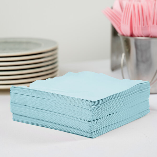 A stack of Creative Converting Pastel Blue paper napkins on a table.