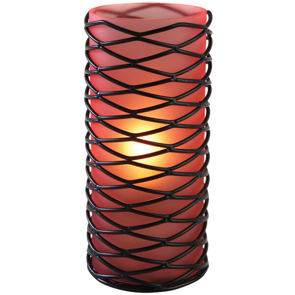 A close-up of a black wire candle holder with a red candle inside.