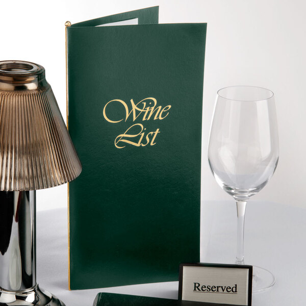 A green Menu Solutions wine list cover on a table with a wine glass