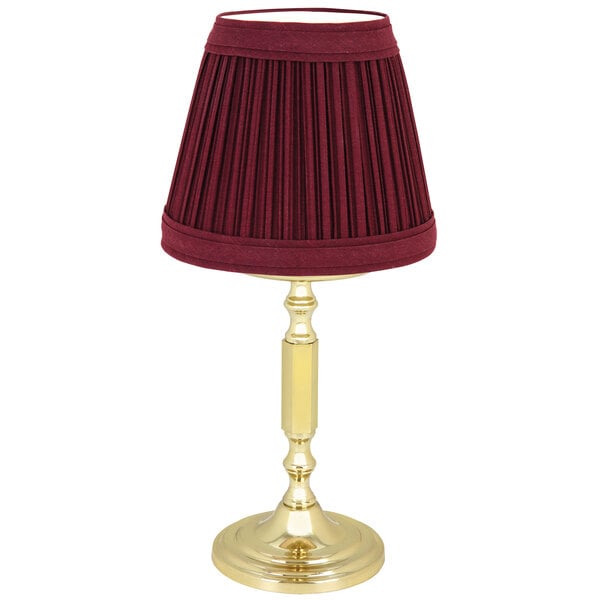 A burgundy lamp shade on a gold Sterno La Rue lamp base.