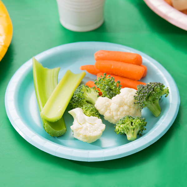 A pastel blue paper plate with broccoli, cauliflower, carrots and celery on it.