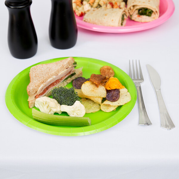 A Creative Converting fresh lime green paper plate with a sandwich and a drink on a table.