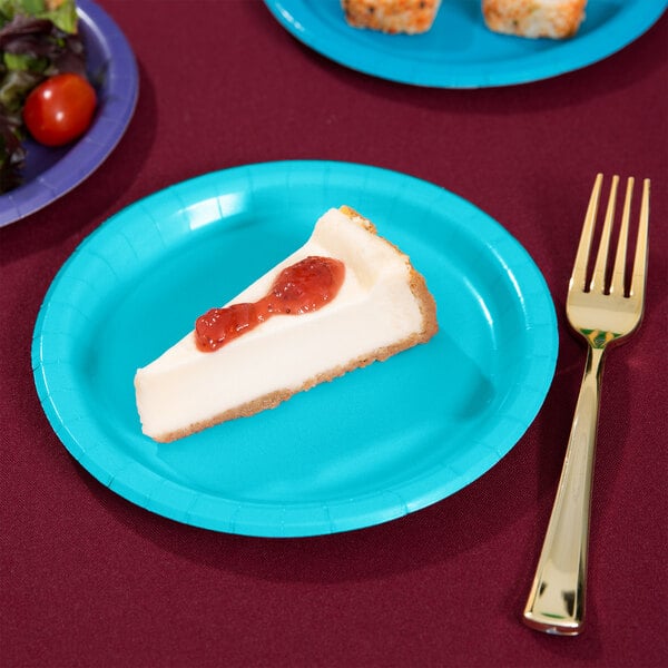 A piece of cheesecake with strawberry jam on a blue Bermuda Blue paper plate with a fork.