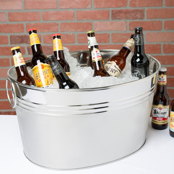 An American Metalcraft stainless steel oval tub filled with ice and beer bottles on a table.