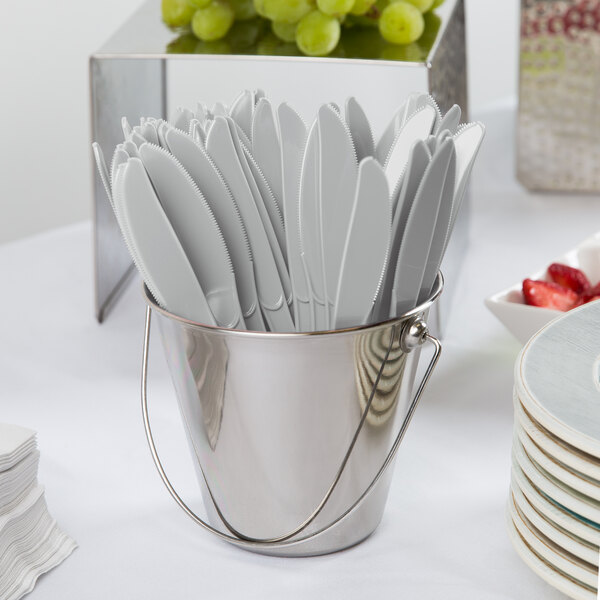 A bucket filled with Creative Converting Shimmering Silver plastic knives.