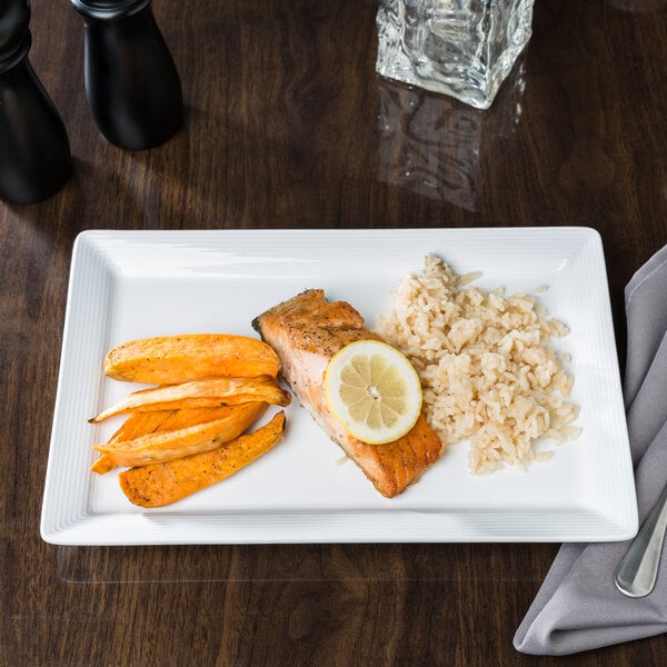 A Libbey white porcelain plate with food including salmon, rice, and a slice of lemon.