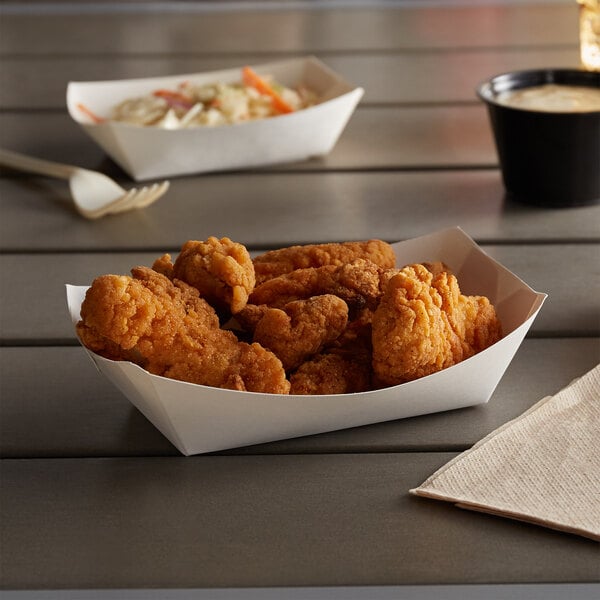 A white paper food tray of fried chicken on a table.