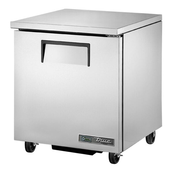 A silver True low profile undercounter freezer with wheels.