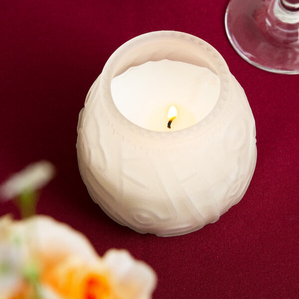 A white Sterno Venetian candle in a white candle holder on a table.
