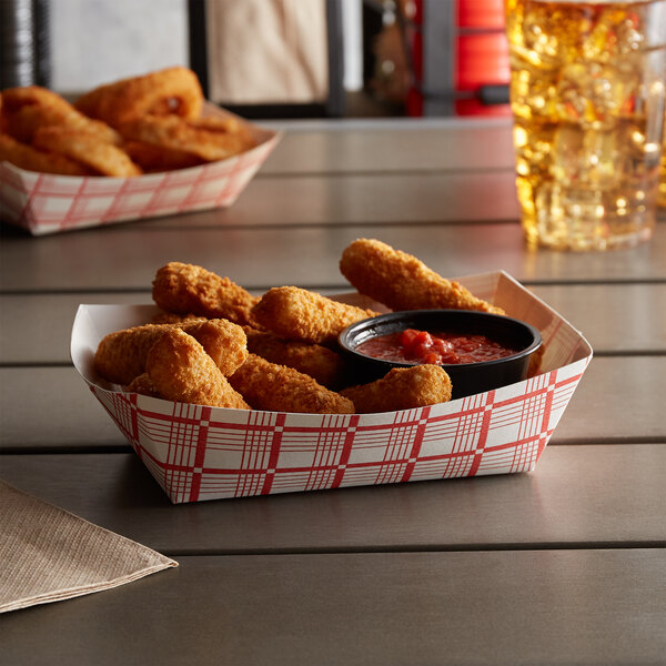 A red check paper food tray filled with fried chicken and sauce.