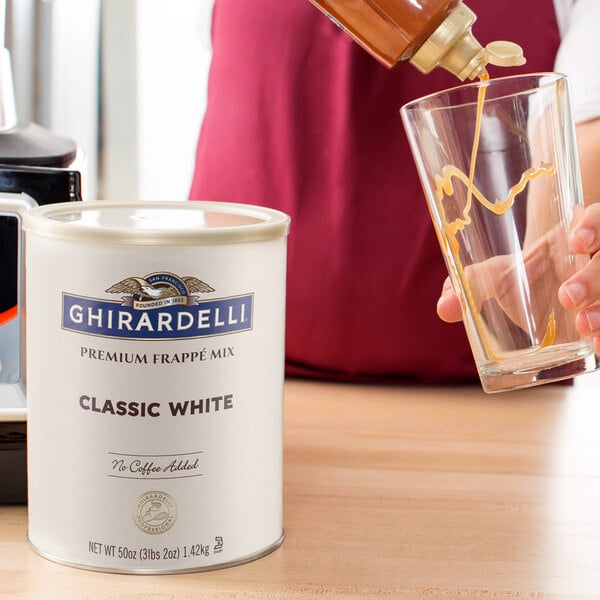 A person pouring Ghirardelli Classic White Frappe Mix into a glass.
