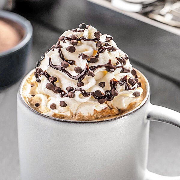 A cup of hot chocolate with whipped cream and Ghirardelli Dark Chocolate 10M Baking Chips.