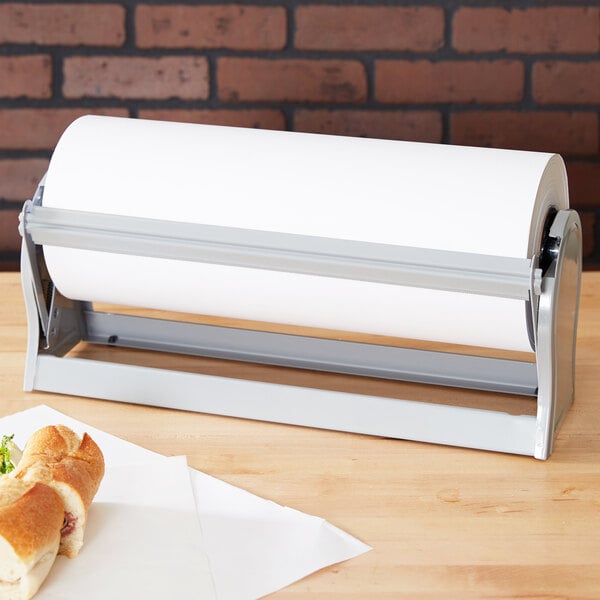 A Bulman gray steel paper dispenser on a table with a sandwich and a roll of paper towels.