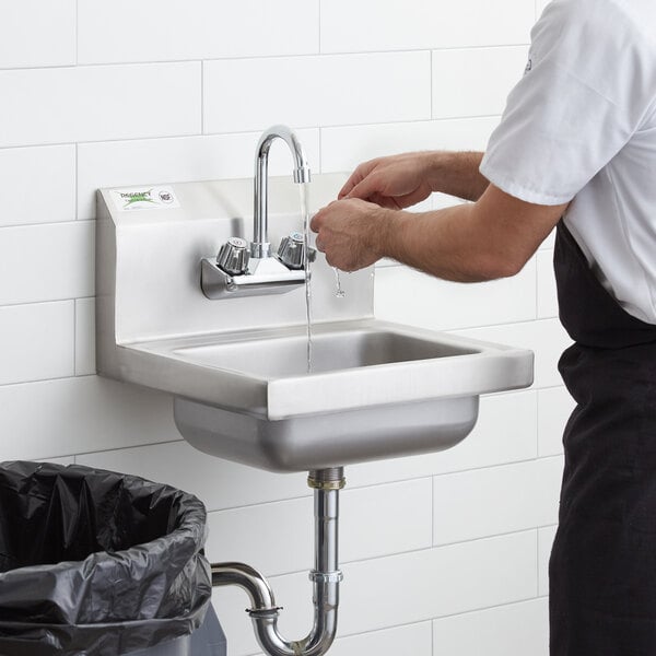A man washing his hands in a Regency wall mounted hand sink.
