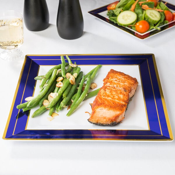 A Fineline white plastic square plate with blue rim and gold bands holding salmon and green beans.