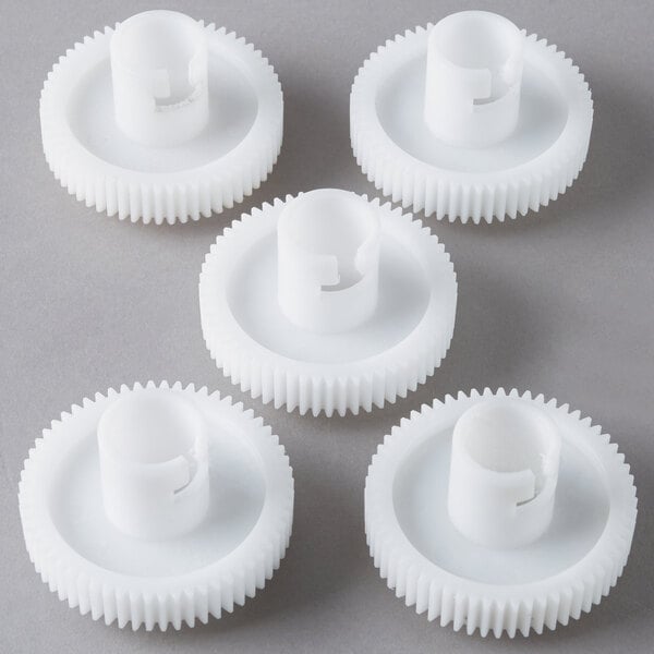 Four white plastic gears on a white surface.