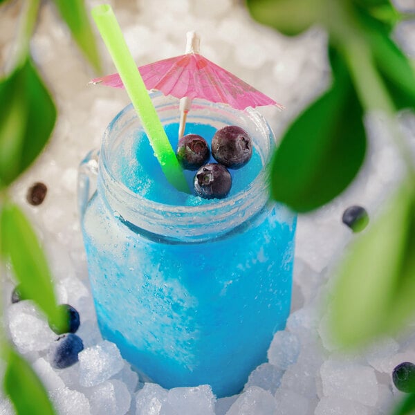 A blue Carnival King Blue Raspberry slushy in a jar with a straw and a pink umbrella.