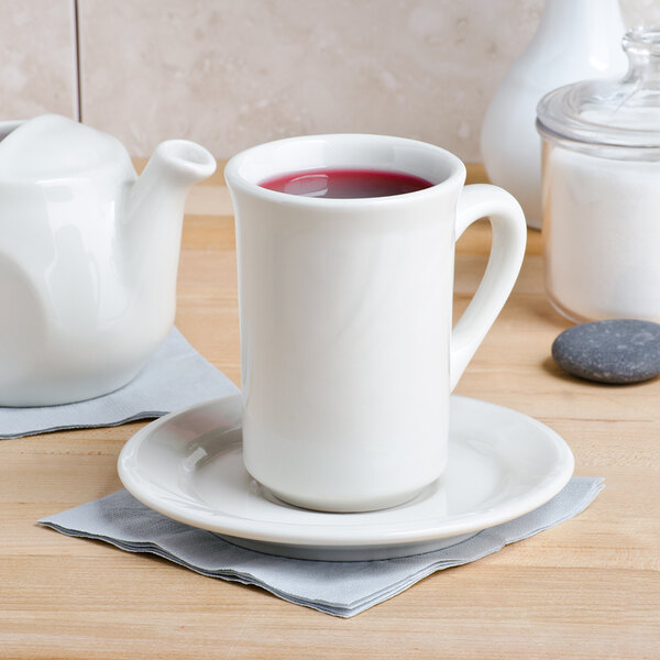 A white Tuxton mug with a red liquid in it.