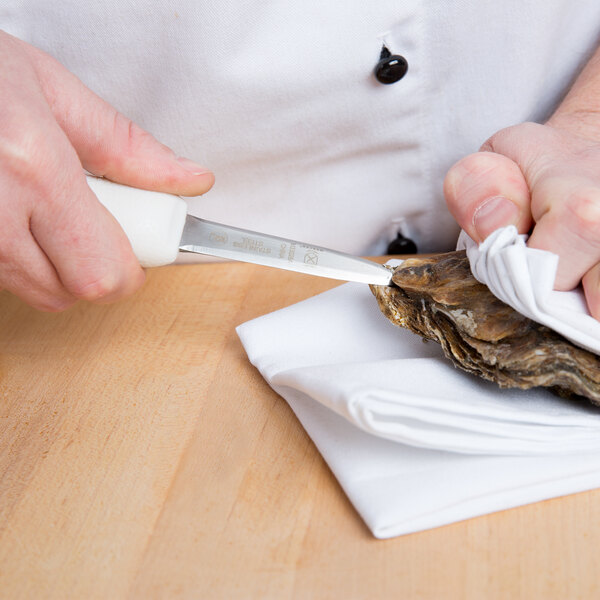 A person using a Mercer Culinary Boston style oyster knife to clean an oyster shell.