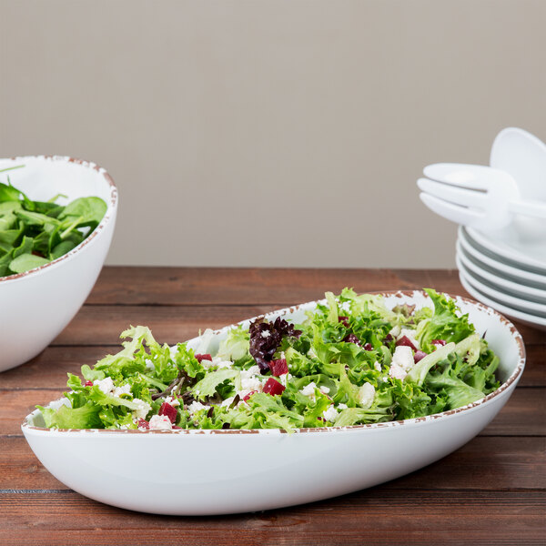 A bowl of salad in a GET Tuscan White melamine bowl on a wood table.