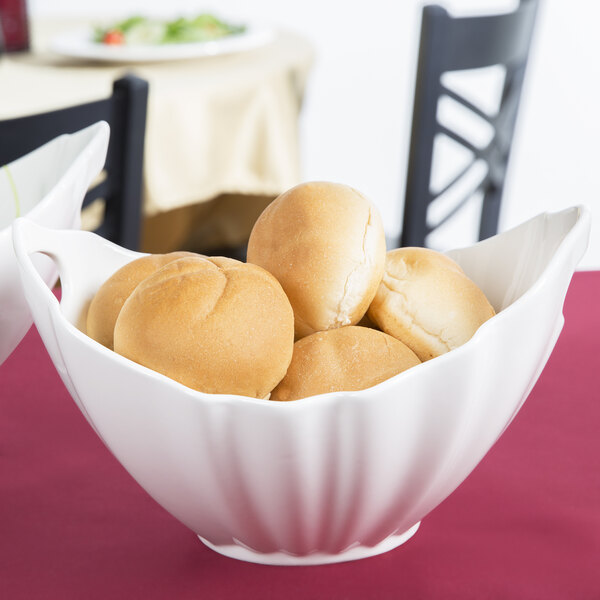 A white 10 Strawberry Street Whittier boat bowl filled with rolls on a table.