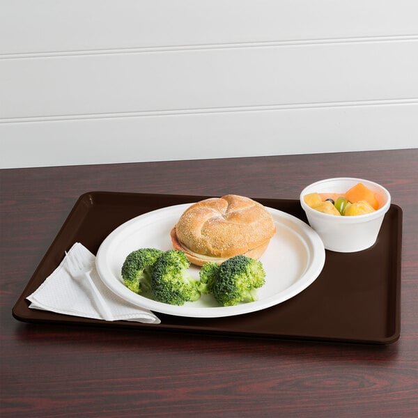 A Brazil brown Cambro dietary tray with a sandwich, broccoli, and fruit on it.