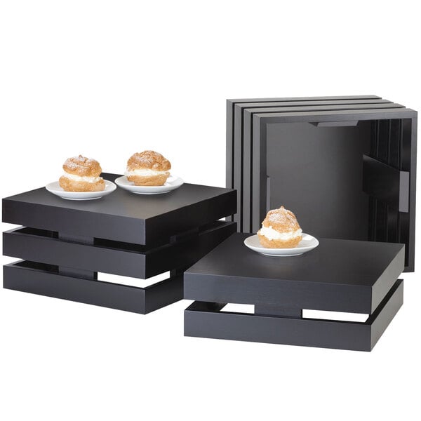 A group of black Cal-Mil square crate risers with desserts on them.