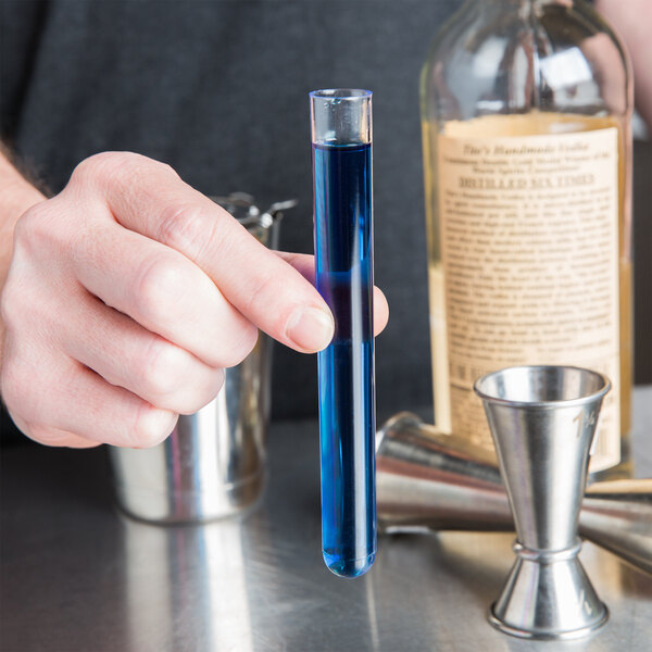 A person holding a Choice Crystal Clear Plastic Test Tube filled with blue liquid.