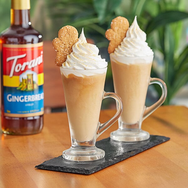 A glass of gingerbread flavored drink with a cookie on the rim.