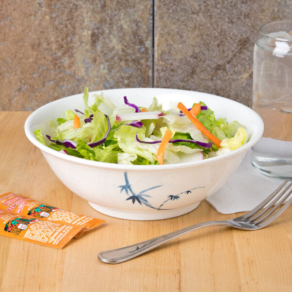 A Blue Bamboo melamine bowl filled with salad with lettuce and carrots and a fork.