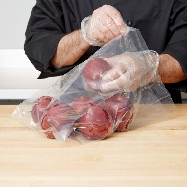 A person in a black apron holding a LK Packaging plastic bag of apples.