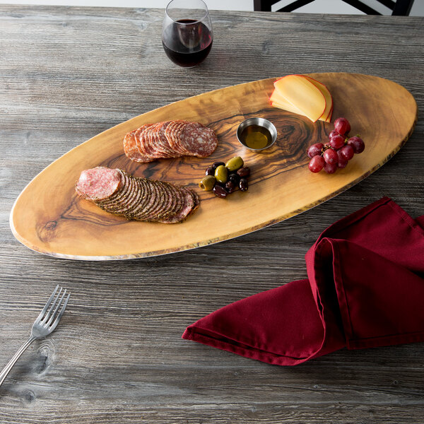 An oval faux olive wood American Metalcraft melamine serving board with a plate of food and a glass of wine on a table.