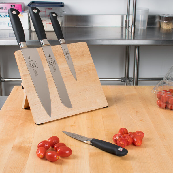 A Mercer Culinary Genesis knife set on a magnetic board with tomatoes.