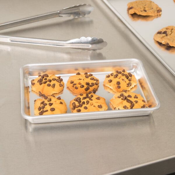 A Vollrath aluminum bun pan with chocolate chip cookies on it.