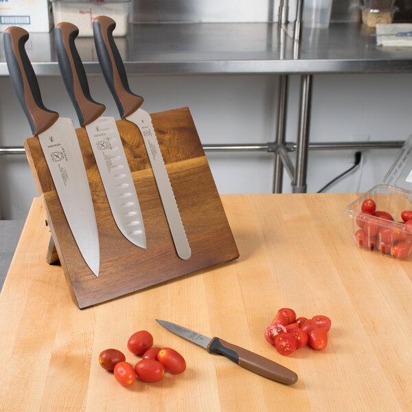A Mercer Culinary Millennia Colors® 5-piece knife set with brown handles on an Acacia magnetic board.