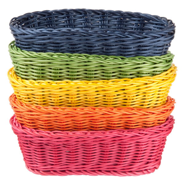 A stack of Tablecraft oval rattan bread baskets in assorted colors.