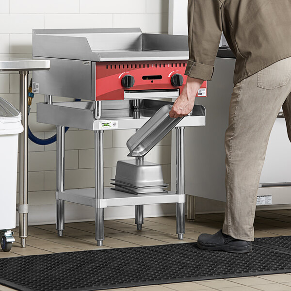 A man using a stainless steel equipment stand in a professional kitchen.