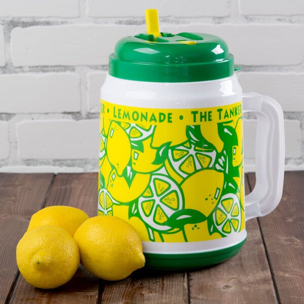 A white and green "The Tanker" lemonade mug with a green lid and yellow lemons next to lemons.