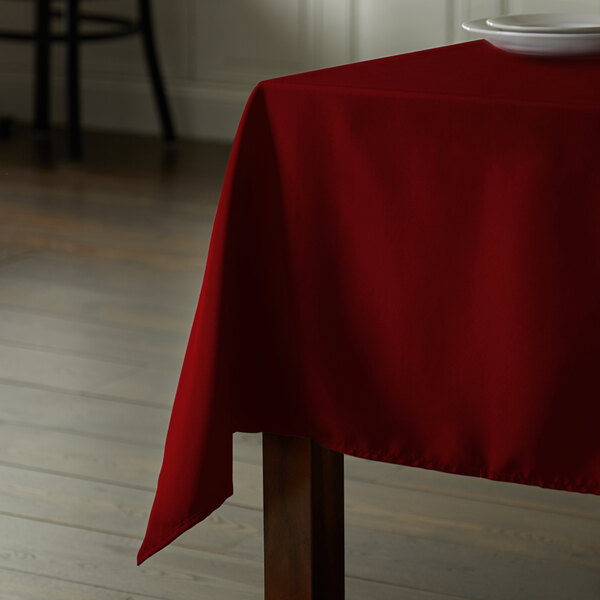 An Intedge burgundy square polyester table cover on a table.