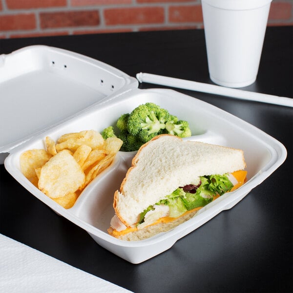 A Dart white foam container with a sandwich, broccoli, and french fries in it.