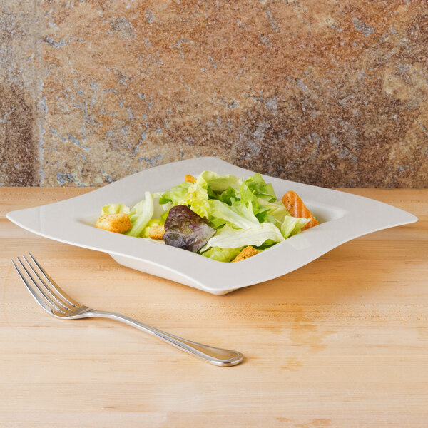 A plate of salad in a Fineline Wavetrends ivory plastic bowl.